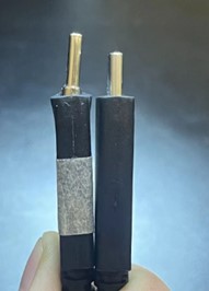 Zwei USB-C-Stecker nebeneinander gehalten, der linke Stecker zeigt einen verbogenen Metallstecker, während der rechte Stecker gerade und unbeschädigt ist